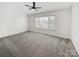 Bright main bedroom featuring a ceiling fan, large window, and plush carpeting at 13424 Kibworth Ln, Charlotte, NC 28273