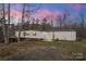 Cozy single-story home featuring a long layout and wooded surroundings during the daytime under pink clouds at 144 Cherokee Ln, New London, NC 28127