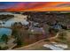 Stunning sunset aerial view of a lakeside community with a golf course, sandy beach, and gorgeous homes at 17429 Staysail Ct, Cornelius, NC 28031