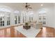 Bright living room with multiple arched windows and doors, light colored furniture, and hardwood flooring at 17429 Staysail Ct, Cornelius, NC 28031