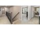 Hallway with wood and iron railing leading to rooms with neutral colors and great lighting at 4660 Ardmore Ln, Harrisburg, NC 28075