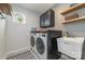 Well-lit laundry room with modern washer and dryer, ample counter space, and stylish herringbone-patterned wallpaper at 4660 Ardmore Ln, Harrisburg, NC 28075