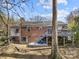 Backyard view of a brick home with a spacious deck and stairs surrounded by mature trees, offering a private outdoor space at 4820 Valley Stream Rd, Charlotte, NC 28209