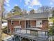 Backyard view of brick home featuring an elevated deck perfect for grilling and outdoor living, with mature trees at 4820 Valley Stream Rd, Charlotte, NC 28209