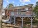 Backyard view of a brick home with a spacious deck for outdoor enjoyment, enhanced by lattice and mature trees at 4820 Valley Stream Rd, Charlotte, NC 28209