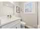 Bright bathroom featuring a modern sink with white cabinets, a window and a framed mirror at 4820 Valley Stream Rd, Charlotte, NC 28209