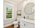 A powder room with a round mirror, marble countertop, and white vanity at 4830 Broad Hollow Dr, Charlotte, NC 28226