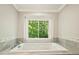 Elegant bathtub with a large window offering serene views of the surrounding greenery at 4830 Broad Hollow Dr, Charlotte, NC 28226