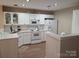 Well-lit eat-in kitchen with white cabinets, stainless steel sink, and serving counter at 5963 Moose Ln, Charlotte, NC 28269