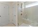 Bathroom with tiled shower featuring glass doors and shelving, as well as a door at 6450 Keeton Ln, Harrisburg, NC 28075