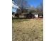 Spacious backyard presents a large grassy area, a charming brick house, and mature trees at 6520 Farmway Pl, Charlotte, NC 28215