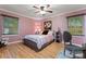 Bedroom with pink walls, wood-look floors, ceiling fan and natural light from two windows at 6721 Old Post Rd, Charlotte, NC 28212