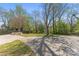 Large backyard with a stone fire pit, concrete pad, green grass and privacy trees at 6914 Idlewild Rd, Charlotte, NC 28212