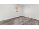 A bright, empty bedroom is seen with hard floors, minimal natural light, and neutral wall colors at 6914 Idlewild Rd, Charlotte, NC 28212