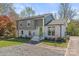Charming two-story home with a gray and white brick exterior, beautiful landscaping, and a vibrant green front door at 6914 Idlewild Rd, Charlotte, NC 28212