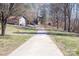 Long concrete driveway leading to a charming home surrounded by mature trees and a well-maintained lawn at 7930 Browne Rd, Charlotte, NC 28269