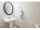 Clean powder room featuring a pedestal sink, round mirror, and essential fixtures at 8009 Whitehawk Hill Rd, Waxhaw, NC 28173