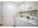 Bright laundry room features white cabinets and appliances with a door leading to the exterior at 9239 Silver Pine Dr, Charlotte, NC 28277
