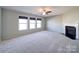 Sunlit living room with a fireplace, ceiling fan, and large windows featuring roman shades at 1000 Sweetgum St, Gastonia, NC 28054