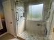 Modern tiled shower features glass enclosure, grab bars, and recessed shelf for convenience at 104 Johnsbury Dr, Stanley, NC 28164