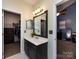 Bathroom featuring a vanity with a dark wood cabinet, mirror and an open doorway to the bedroom at 12729 Mcginnis Ln, Huntersville, NC 28078