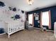 Bedroom with blue accent wall, floral wallpaper, and a white crib at 12729 Mcginnis Ln, Huntersville, NC 28078