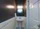 Stylish powder room with pedestal sink, decorative mirror, and elegant lighting at 12729 Mcginnis Ln, Huntersville, NC 28078