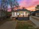 Charming home with a welcoming front porch and updated landscaping, featuring a unique, colorful sky at sunset at 133 2Nd Ave, China Grove, NC 28023