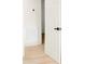 Hallway featuring light wood floors and white walls, with a partially open door and black hardware at 188 Bailey Rd, Mooresville, NC 28117