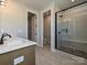 Modern bathroom featuring dual sinks, a walk-in shower with glass doors, and neutral tiling at 209 Halemarg Dr, Belmont, NC 28012