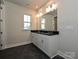 Bright bathroom featuring double vanity with black countertop, white cabinets, and modern lighting fixtures at 211 Halemarg Dr, Belmont, NC 28012