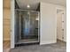 Modern bathroom featuring a glass-enclosed shower with black marble accents and gray tile flooring at 211 Halemarg Dr, Belmont, NC 28012