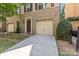 Brick townhouse featuring a one-car garage, driveway, front door, and some landscaping in front at 225 Lincoln St, Charlotte, NC 28203