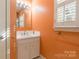 Small bathroom with vanity, sink, mirror, white cabinets, and coral colored walls at 406 Forest Dr, York, SC 29745