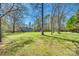 Expansive back yard with mature trees and a charming blue house in a serene, natural setting at 6688 Pine Forest Dr, York, SC 29745