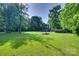 Vast backyard with a fire pit, surrounded by lush greenery and a charming blue house, ideal for outdoor enjoyment at 6688 Pine Forest Dr, York, SC 29745