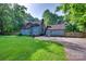 Expansive backyard featuring lush lawn, a detached garage, and a charming blue home nestled among mature trees at 6688 Pine Forest Dr, York, SC 29745