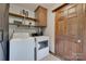 Well-lit laundry room with washer, dryer, shelves, and wooden door at 6688 Pine Forest Dr, York, SC 29745