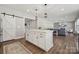 Modern kitchen island with white cabinets and stylish lighting, flowing into the living area with a cozy fireplace at 8310 Sandstone Crest Ln, Indian Land, SC 29707