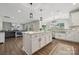 Open-concept kitchen with white island and countertops with stainless steel appliances and hardwood flooring at 8310 Sandstone Crest Ln, Indian Land, SC 29707