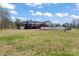 View of the back of the property with a wooden deck and covered patio, white fence, and lots of green grass at 1030 Hurley School Rd, Salisbury, NC 28147