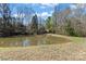 A view of a pond with bare trees in the background and green grass in the foreground at 1030 Hurley School Rd, Salisbury, NC 28147