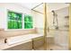 Modern bathroom featuring a glass enclosed shower, soaking tub and a window with forest views at 1080 Rolling Green Dr, Newton, NC 28658