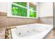 Bright bathroom showcasing a soaking tub with jets, gold fixtures, and a large window at 1080 Rolling Green Dr, Newton, NC 28658