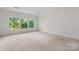 Sunlit bedroom with large windows providing scenic views of the surrounding trees and beige carpet at 1080 Rolling Green Dr, Newton, NC 28658