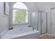 Bright bathroom with a large tub, glass-enclosed shower, and large window at 10845 Hellebore Rd, Charlotte, NC 28213