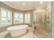 Luxurious bathroom featuring a freestanding tub and a glass-enclosed shower, complemented by natural light at 13358 Bally Bunnion Way, Davidson, NC 28036