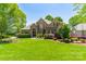 Charming brick home boasts manicured landscaping, a lush lawn, and mature trees at 13358 Bally Bunnion Way, Davidson, NC 28036