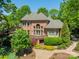 Brick home featuring a manicured lawn, mature trees, a deck, and beautiful landscaping at 13358 Bally Bunnion Way, Davidson, NC 28036