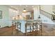 Kitchen island with seating, granite countertops, and modern white cabinetry next to wood staircase at 13358 Bally Bunnion Way, Davidson, NC 28036